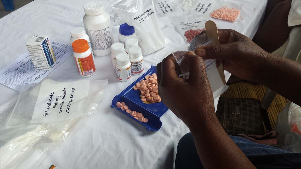 Hands counting tablets on a clinic table