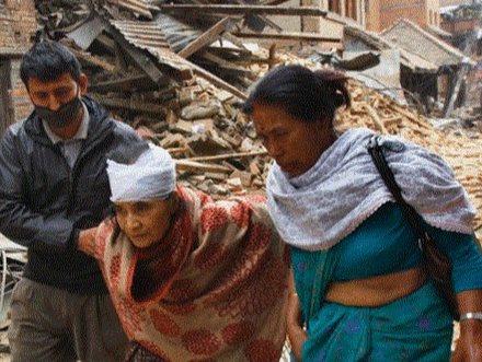 An injured woman being helped through earthquake rubble in Nepal